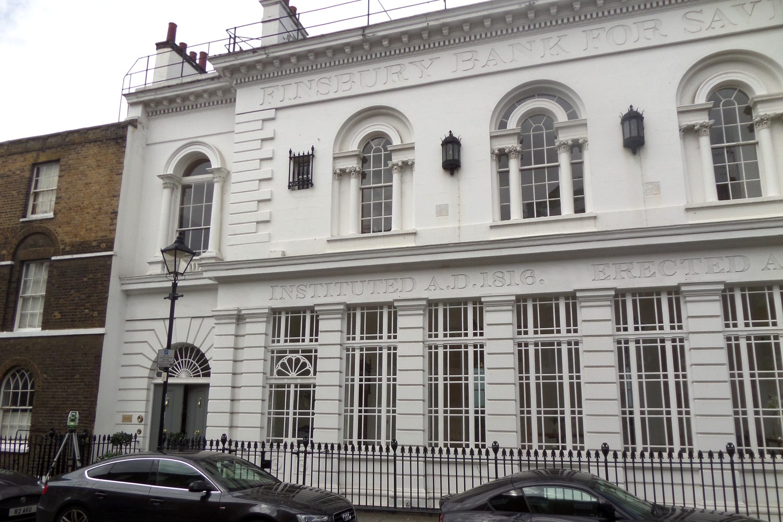 The white stucco front of Finsbury Bank for Savings on Sekforde Street, with its arched first-floor windows and black railings